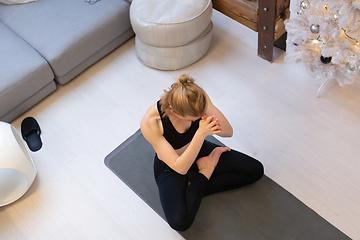 Image showing Beautiful blonde woman doing home workout indoors. Woman practice yoga at home. Fit girl using workout tutorials for healthy active lifestyle. Woman using quarantine for home workouts.