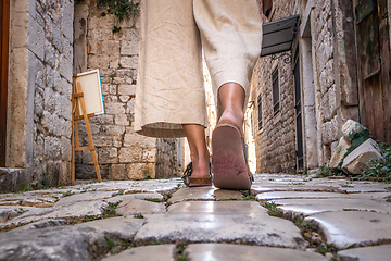 Image showing Detail shot of female legs wearing comfortable travel sandals walking on old medieval cobblestones street dring sightseeing city tour. Travel, tourism and adventure concept