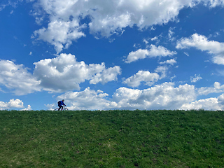 Image showing An unidentified man ride mountain bike on a country road 