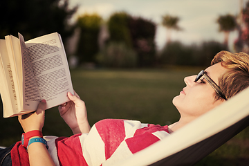 Image showing woman reading a book while relaxing on hammock