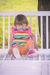 Image showing cute little girl sitting on wooden bench