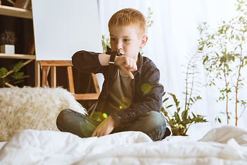 Image showing Little boy using different gadgets at home