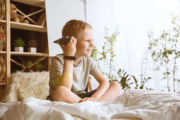 Image showing Little boy using different gadgets at home