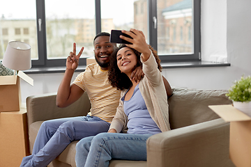 Image showing happy couple moving to new home and taking selfie