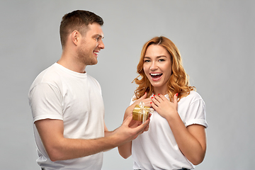 Image showing happy couple in white t-shirts with christmas gift