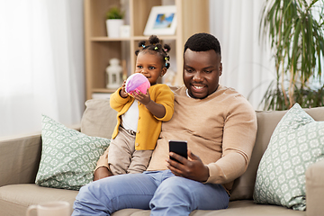 Image showing father with smartphone and baby daugter at home