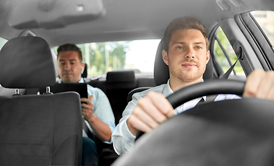 Image showing male taxi driver driving car with passenger