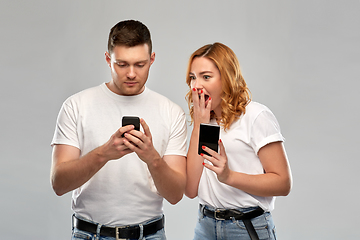 Image showing happy couple in white t-shirts with smartphones