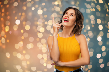 Image showing happy smiling young woman pointing finger up