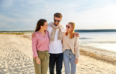 Image showing happy friends walking along summer beach