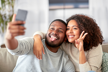 Image showing happy couple with smartphone taking selfie at home