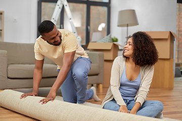 Image showing happy couple with carpet moving to new home