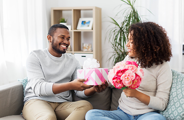 Image showing happy couple with flowers and gift at home