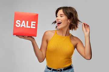 Image showing happy smiling young woman posing with sale sign