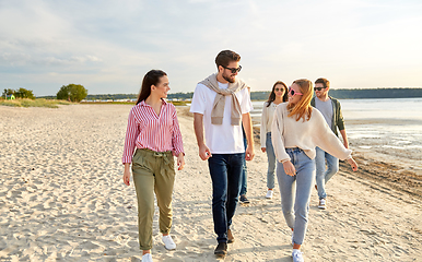 Image showing happy friends walking along summer beach