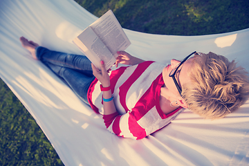 Image showing woman reading a book while relaxing on hammock