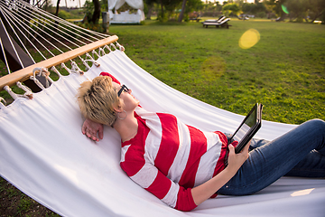 Image showing woman using a tablet computer while relaxing on hammock