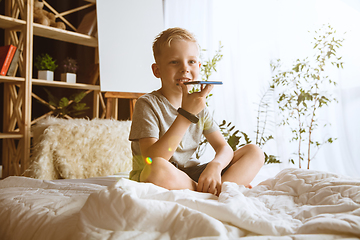 Image showing Little boy using different gadgets at home