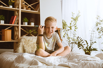 Image showing Little boy using different gadgets at home