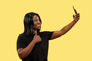 Image showing Young african woman isolated on yellow studio background, facial expression