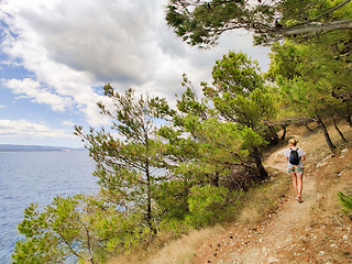 Image showing Young active feamle tourist wearing small backpack walking on co