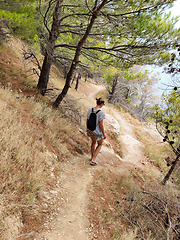 Image showing Young active feamle tourist wearing small backpack walking on co