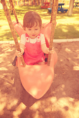 Image showing little girl swinging  on a playground