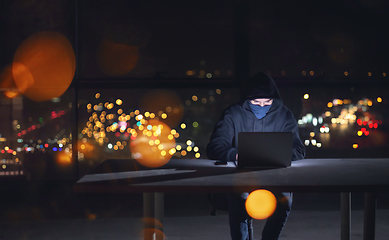 Image showing hacker using laptop computer while working in dark office