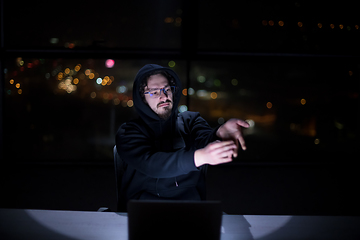 Image showing hacker using laptop computer while working in dark office