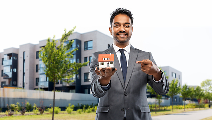 Image showing indian man realtor with house model on city street