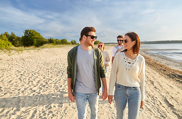 Image showing happy friends walking along summer beach