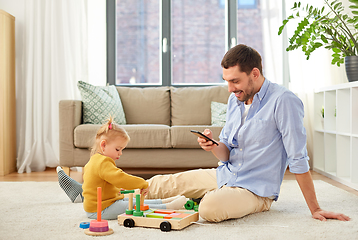 Image showing father with smartphone and baby daughter at home