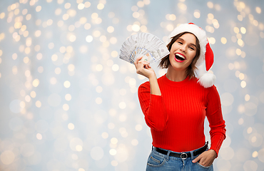 Image showing happy woman in santa hat with money on christmas