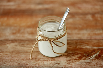 Image showing yogurt or sour cream in glass jar on wooden table