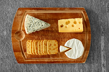 Image showing different cheeses and crackers on wooden board