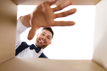 Image showing happy young man looking into open gift box