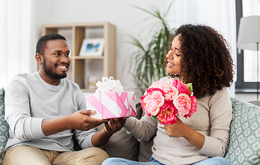 Image showing happy couple with flowers and gift at home