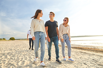 Image showing happy friends walking along summer beach