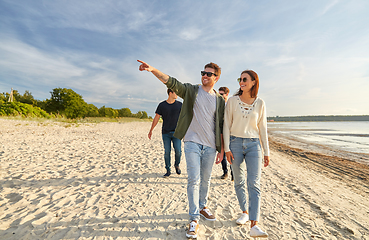 Image showing happy friends walking along summer beach