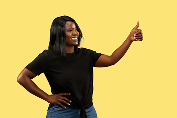 Image showing Young african woman isolated on yellow studio background, facial expression