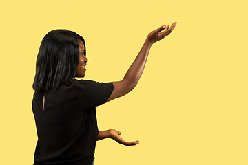 Image showing Young african woman isolated on yellow studio background, facial expression