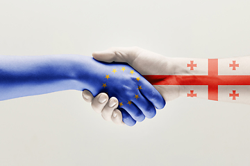 Image showing Two hands. Flag of the European Union. Flag of Georgia.