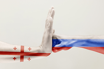 Image showing Two hands. Flag of Russian Federation. Flag of Georgia.