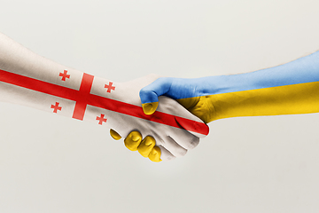 Image showing Two hands. Flag of Georgia. Flag of Ukraine.