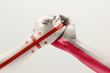 Image showing Two hands. Flag of Georgia. Flag of Poland.