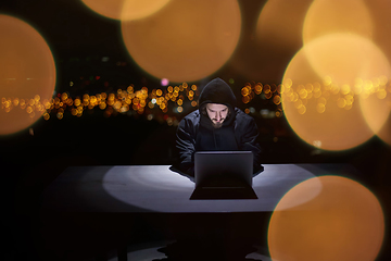 Image showing hacker using laptop computer while working in dark office