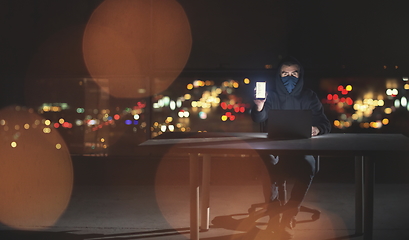 Image showing hacker using laptop computer while working in dark office