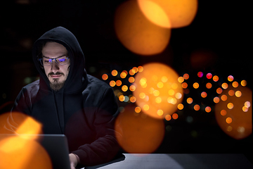 Image showing hacker using laptop computer while working in dark office