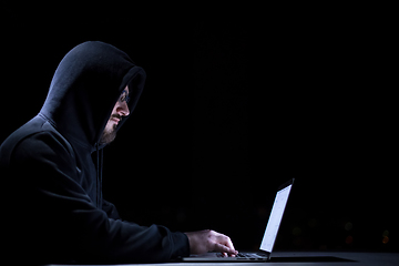 Image showing hacker using laptop computer while working in dark office