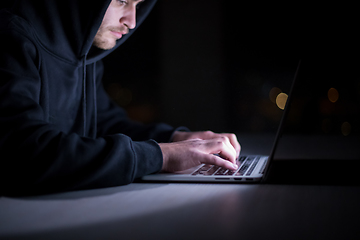 Image showing hacker using laptop computer while working in dark office